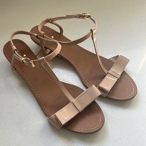 Nude patent leather Kate spade sandal with 1.5” wedge, strap w/buckle, bow